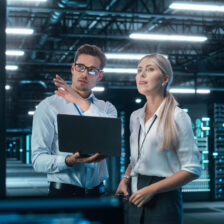 Successful Data Center IT Specialist Using Laptop Computer. Server Farm Cloud Computing Facility with System Administrator Working. Data Protection Engineering Network for Cyber Security.
